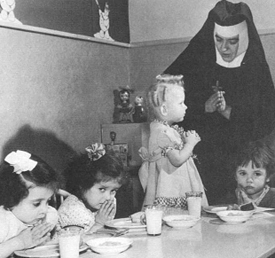 This a black and white photo of a religious sister caring for children in an orphanage.